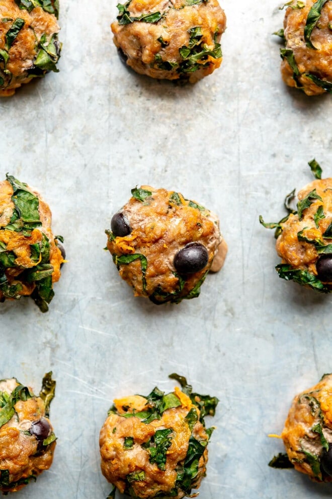 Up close photo of 9 blueberry breakfast meatballs on a metal sheet pan.