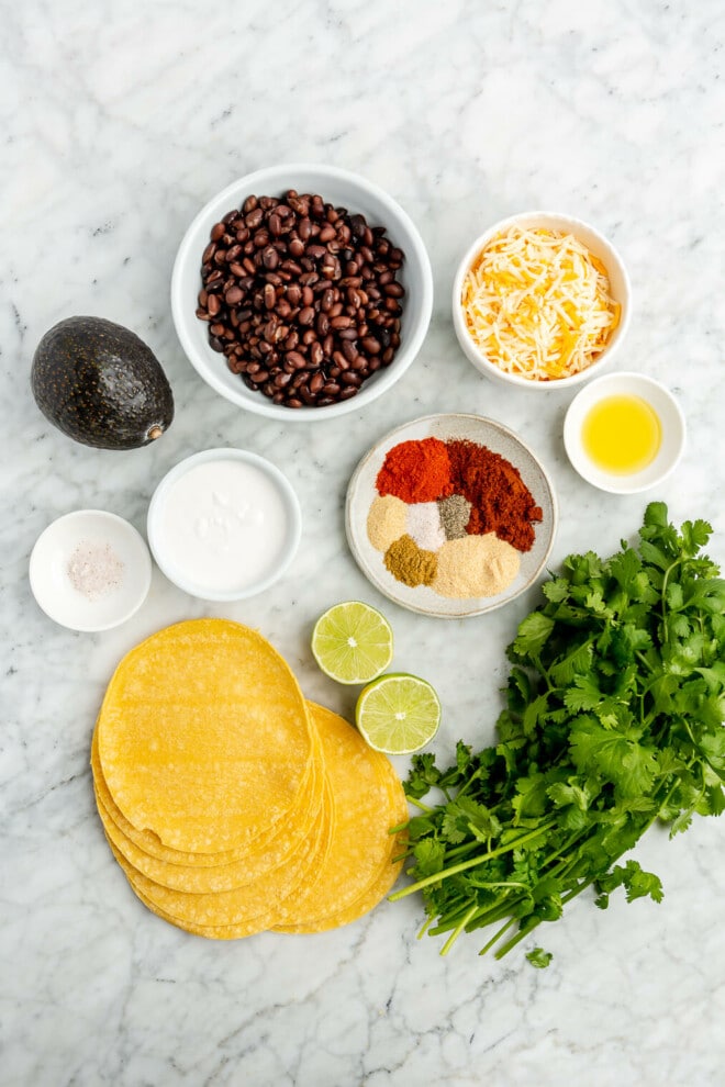 Black bean taco ingredients on a grey and white marble surface.