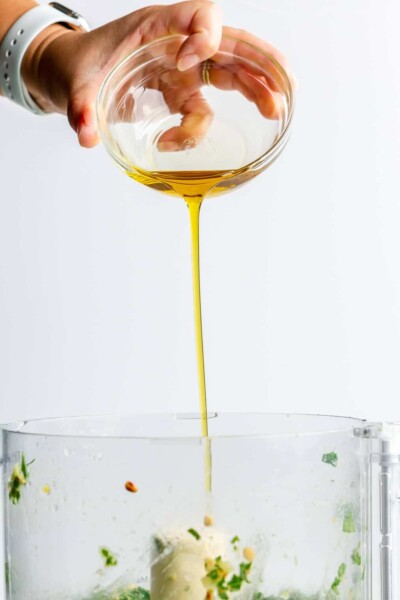 Olive oil being poured into a food processor.
