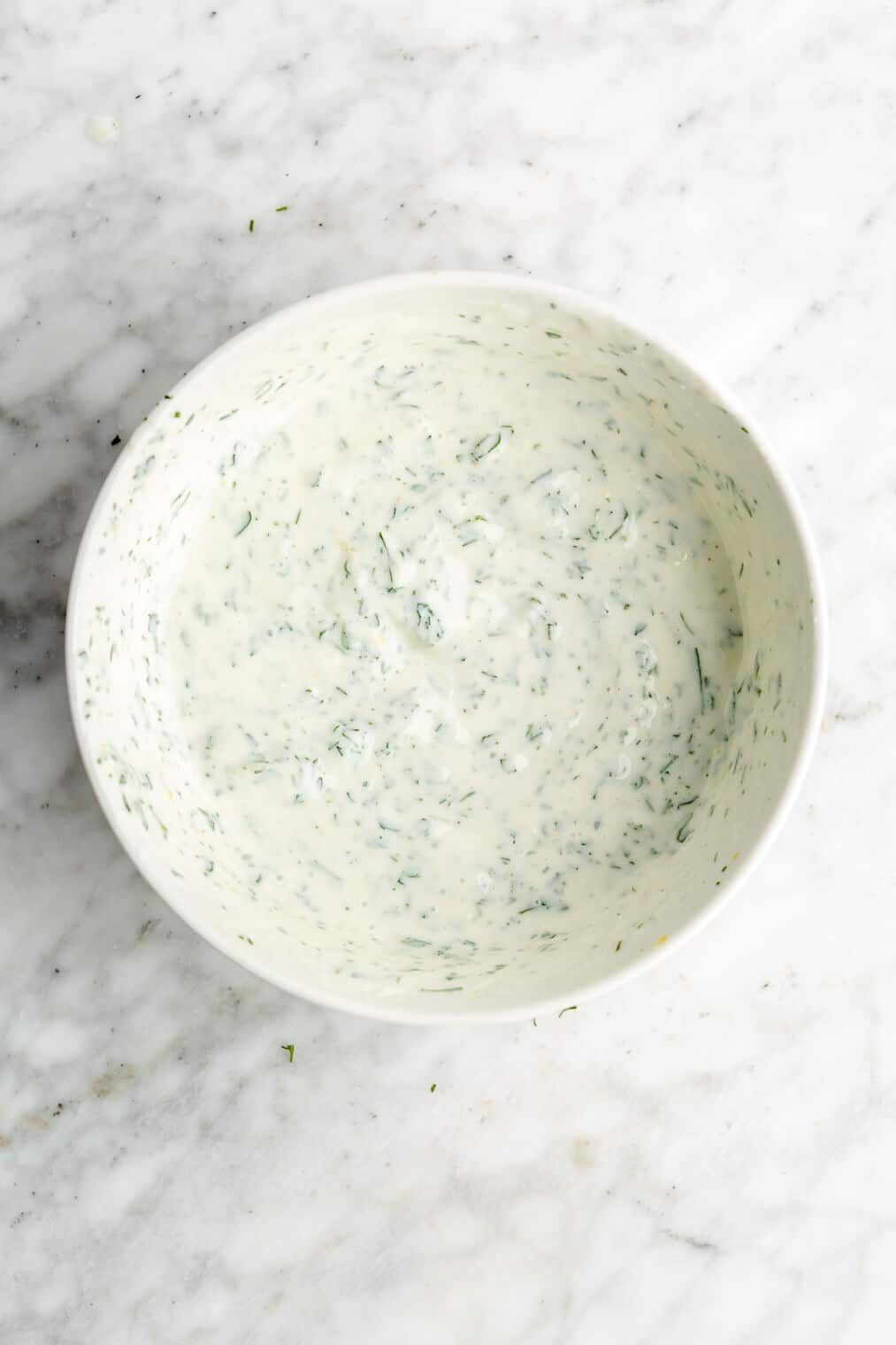A white bowl of a creamy, herby sauce.