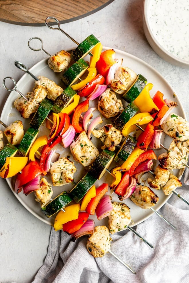 6 chicken and veggie kabobs on a large plate.