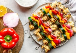 6 chicken and veggie kabobs on a large plate.