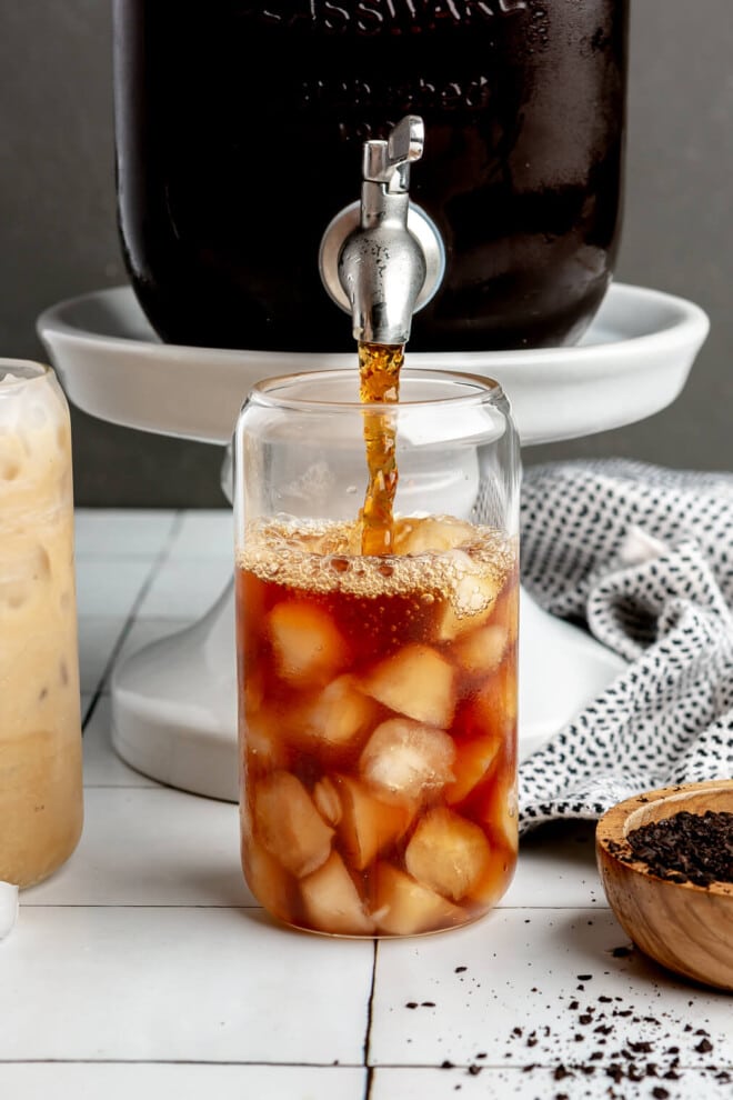 A person using a spout to pour cold brew into an iced glass.