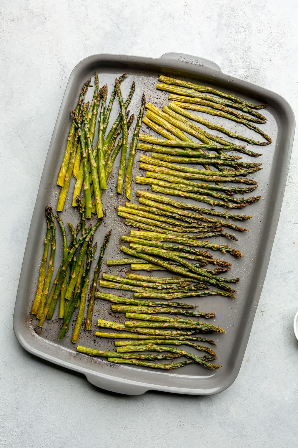 A zoomed out top view of roasted asparagus on a sheet pan.