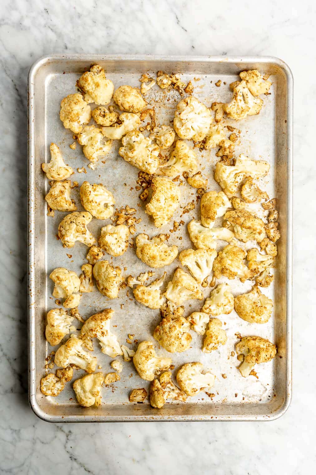 A sheet pan of partially cooked cauliflower florets.
