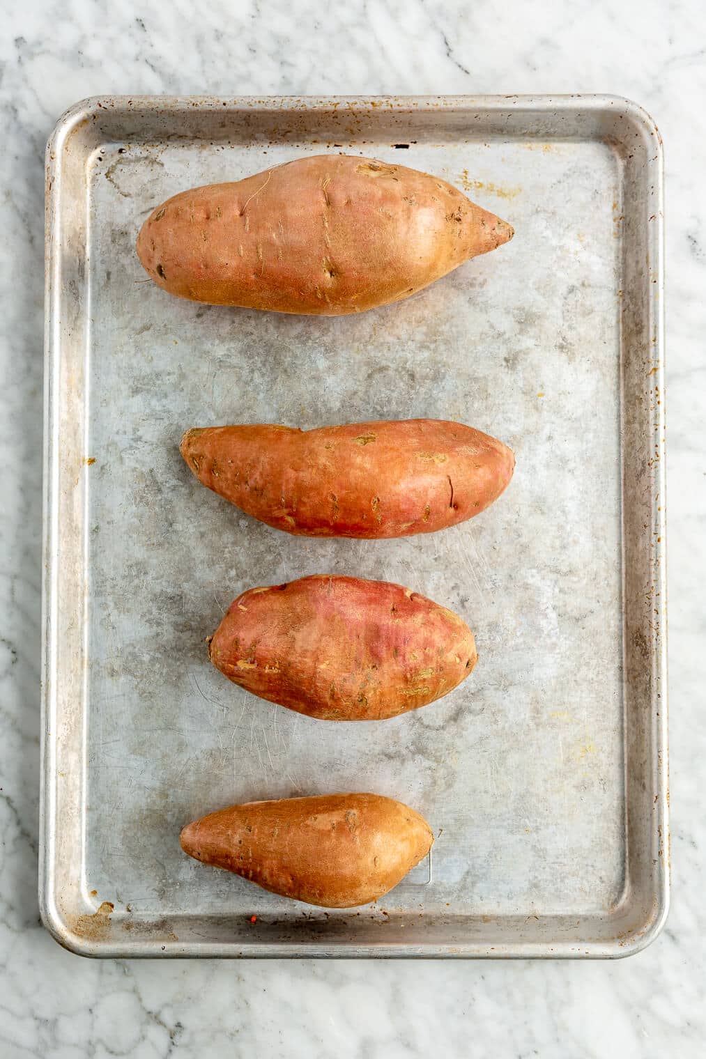4 sweet potatoes on a sheet pan.