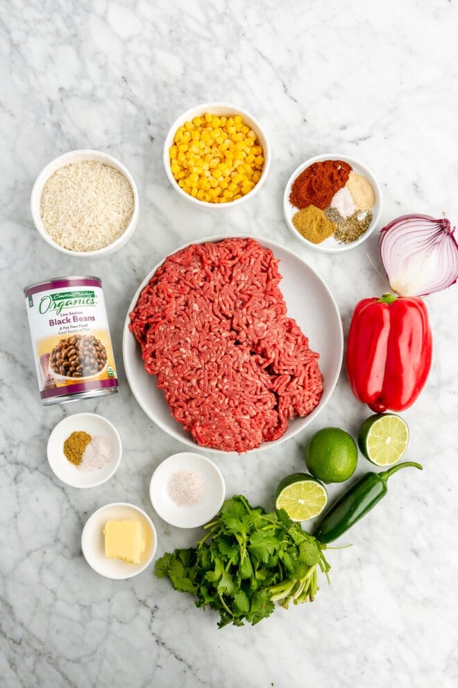 All of the ingredients for ground beef burrito bowls on a marble surface.