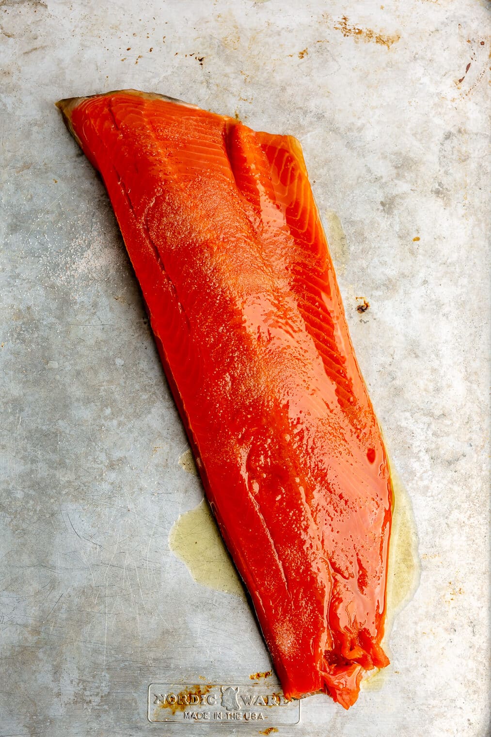 A large raw filet of salmon on a sheet pan.