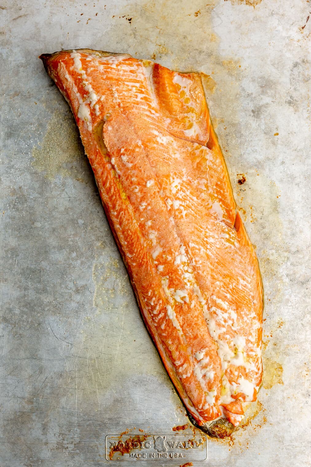 A large cooked filet of salmon on a sheet pan.