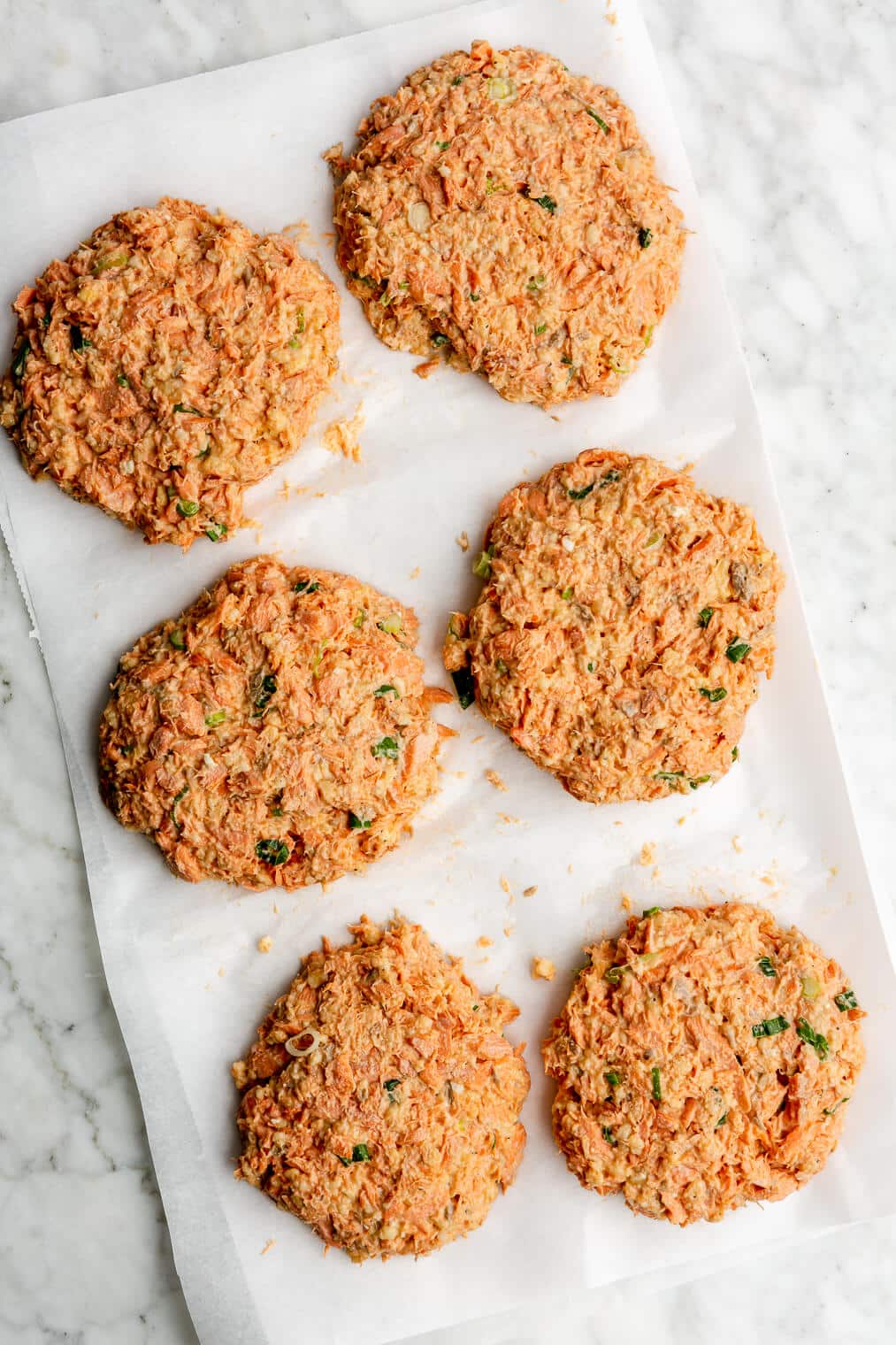 6 salmon cakes (before being cooked) on parchment paper.