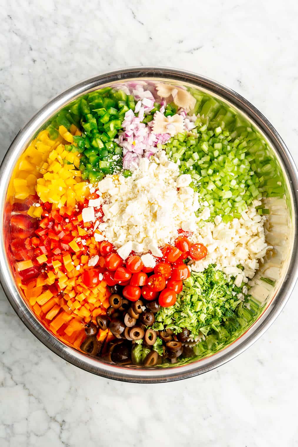 All of the ingredients for an Italian pasta salad in a large metal bowl.