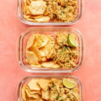 Three meal prep containers of smoky chicken salad next to crackers and a lime wedge.