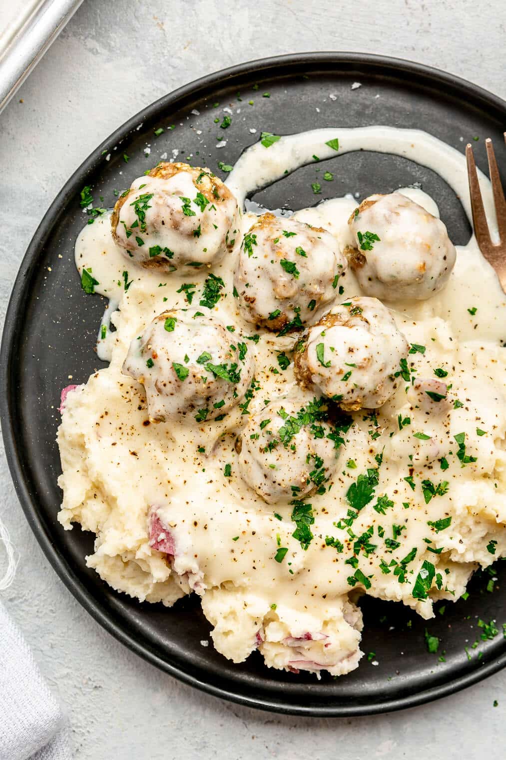A plate of mashed potatoes and Swedish meatballs with gravy.