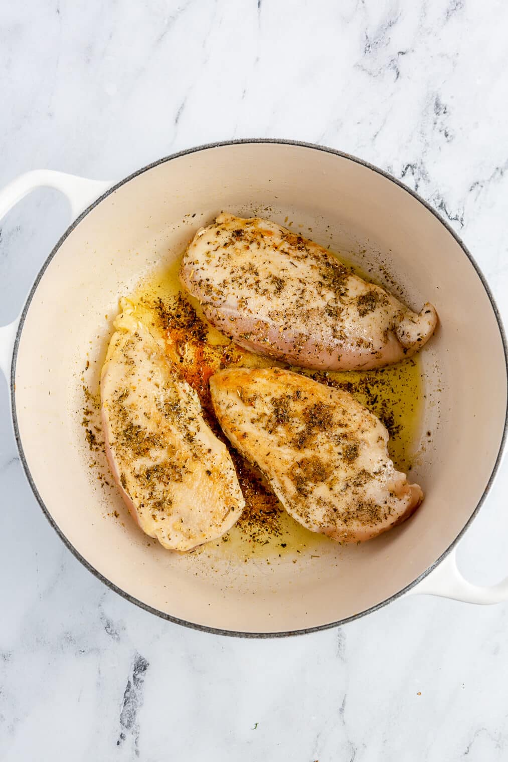 3 large chicken breasts dusted with salt and Italian seasoning searing in a large enameled cast iron pot.
