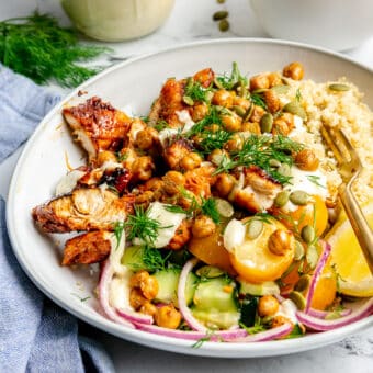 A chicken quinoa bowl topped with veggies, fresh dill, homemade garlic aioli, pumpkin seeds, and air fryer chickpeas.