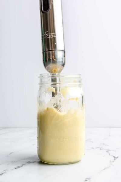 Emulsified egg and oil (creating mayo) in a large mason jar with an immersion blender sticking out of it.