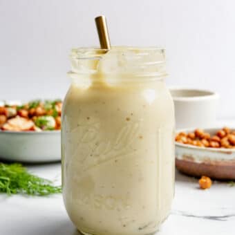 A large mason jar of garlic aioli in front of a chicken quinoa bowl and a small bowl of air fryer chickpeas.