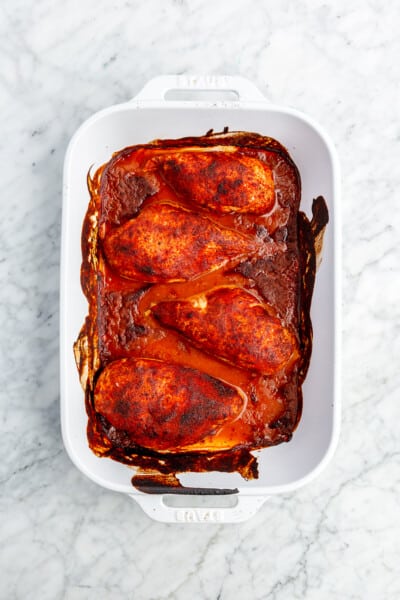 4 bbq baked chicken breasts in a white baking dish.