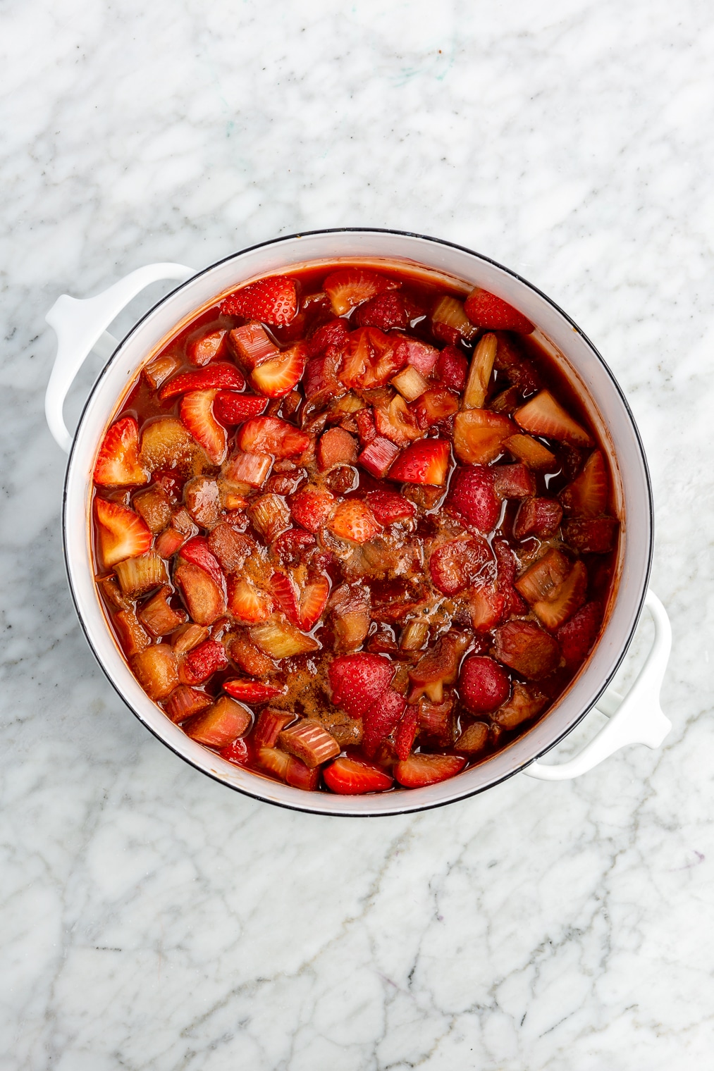 Strawberries and rhubarb in a large dish before being topped with a crumble topping for a strawberry rhubarb crisp.