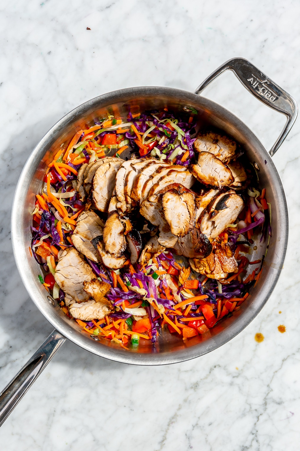 Pork and veggie stir fry in a stainless steel pan.