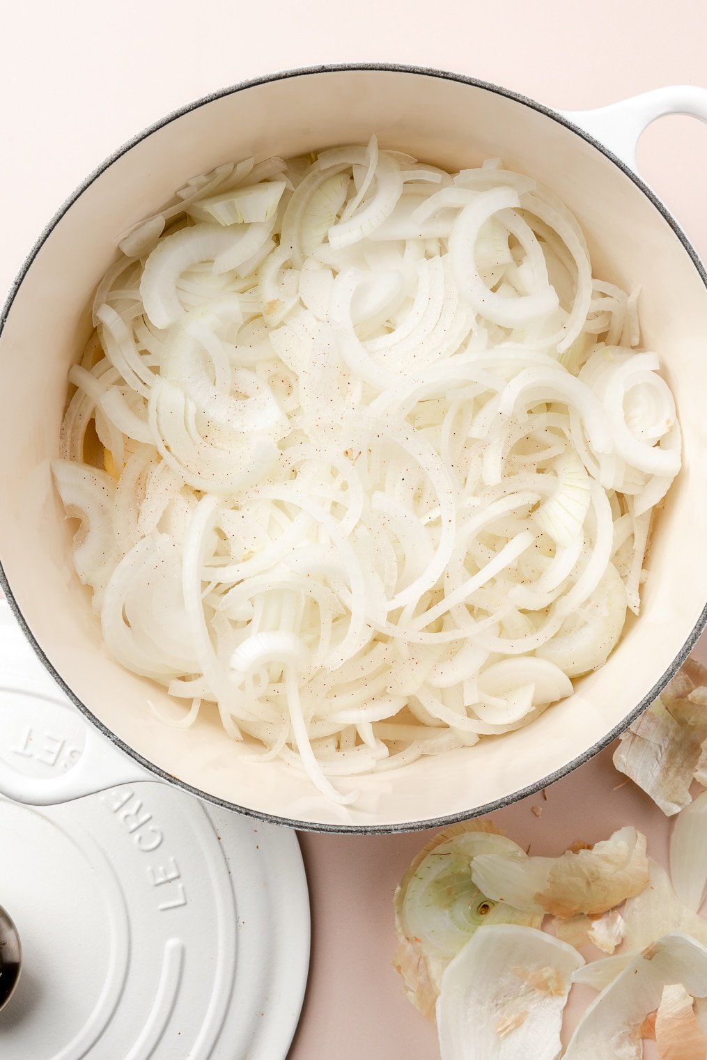 A large enameled cast iron pot filled with butter and sliced onions for caramelized onions.