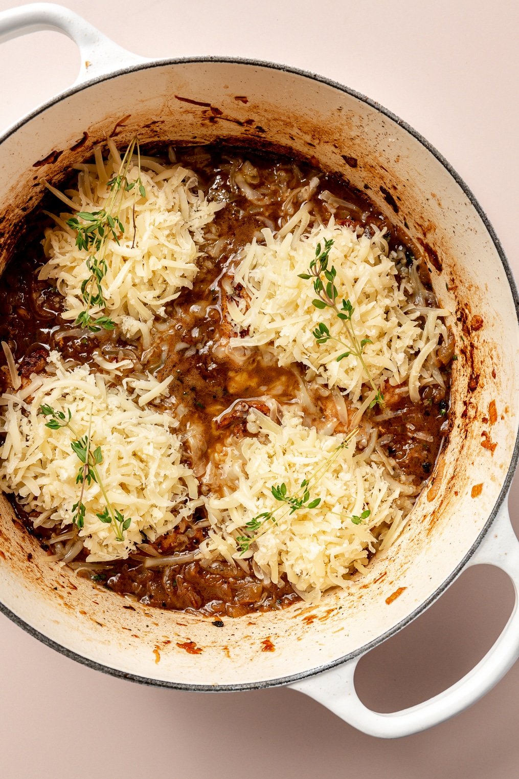 A french onion skillet bake in a large enameled cast iron pot before going into the oven.