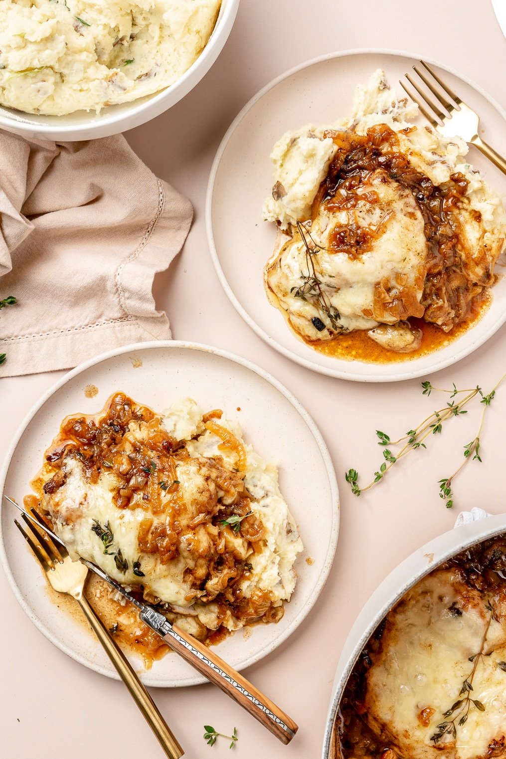 A french onion chicken breast smothered in gruyere cheese and caramelized onions next to mashed potatoes.