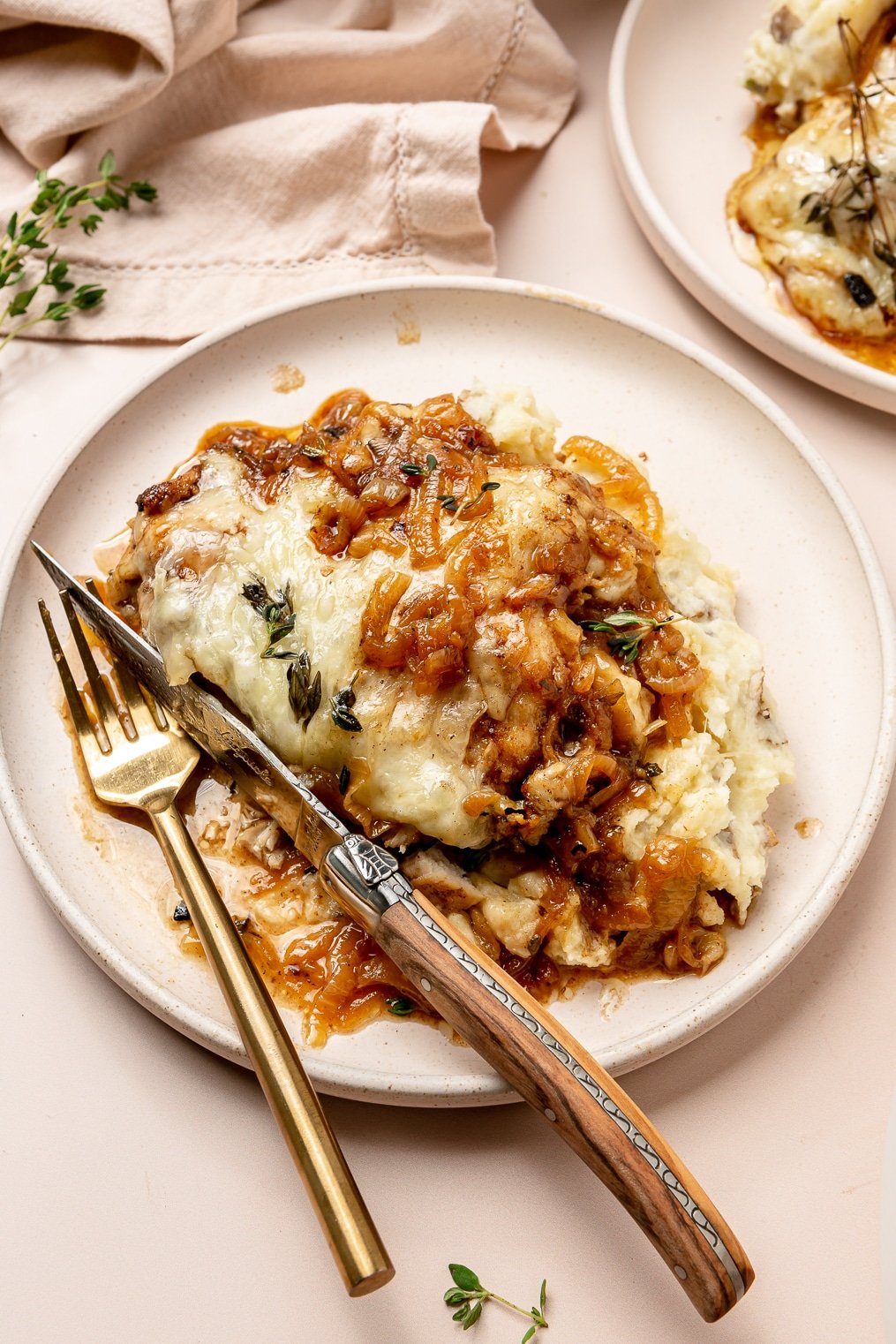 A french onion chicken breast smothered in gruyere cheese and caramelized onions next to mashed potatoes.