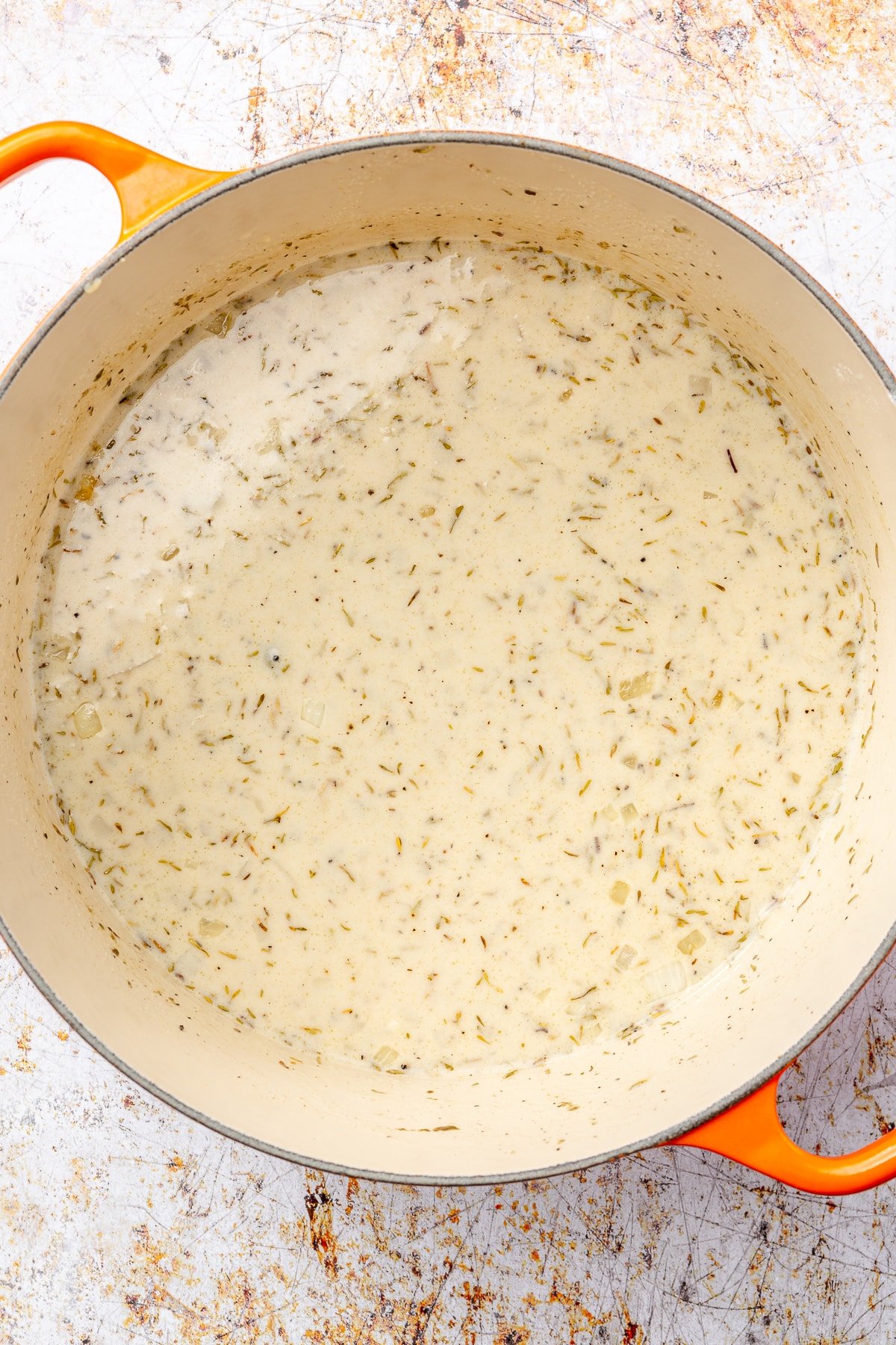 A creamy mixture of spices and sits in an enameled pot.