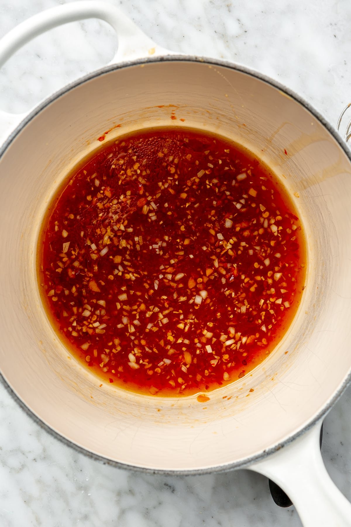 A variety of ingredients and a red sauce are shown in a non stick, stovetop pan after mixing.