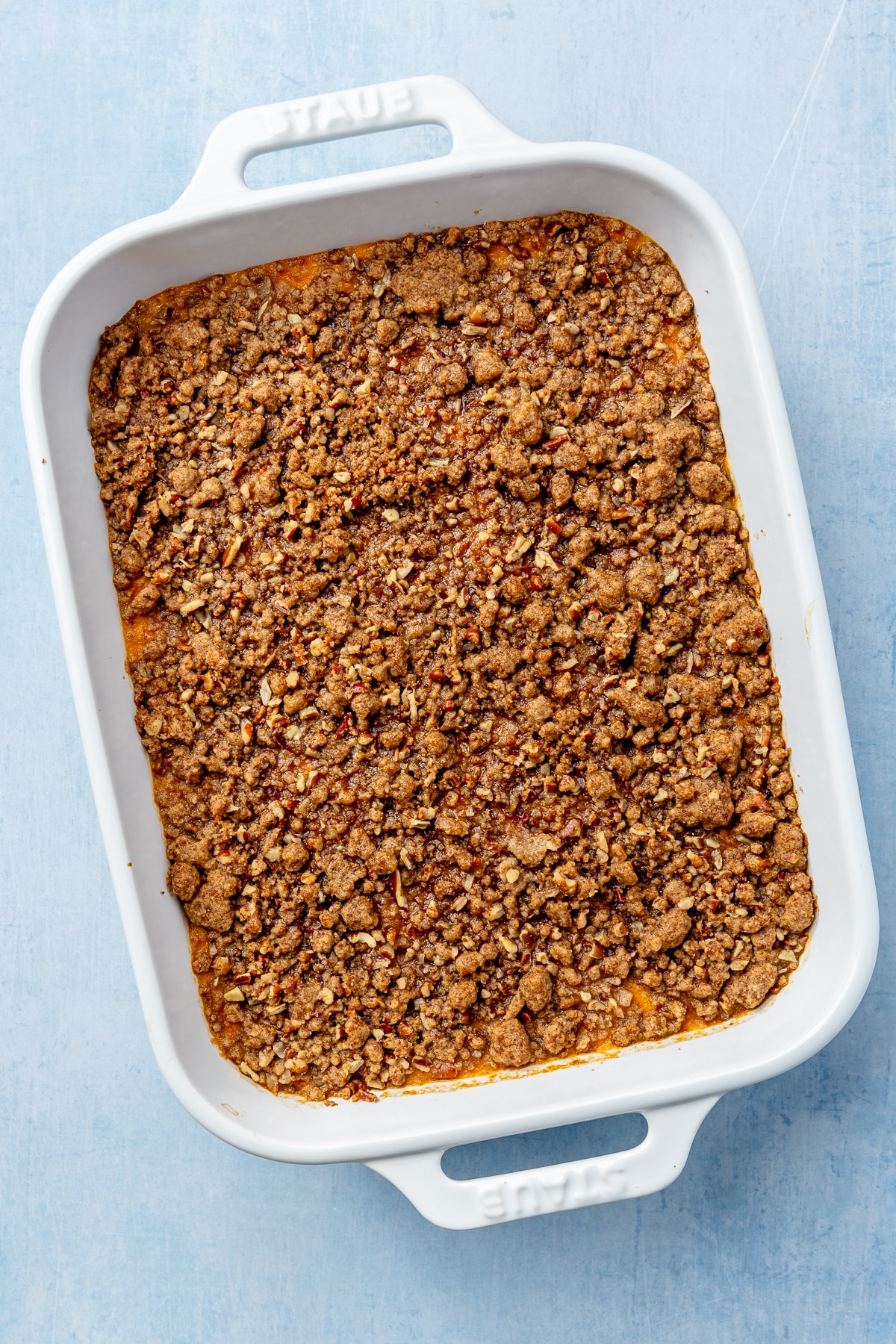 A baked sweet potato mixture, topped with a brown crumble sits, baked, in a white baking dish.