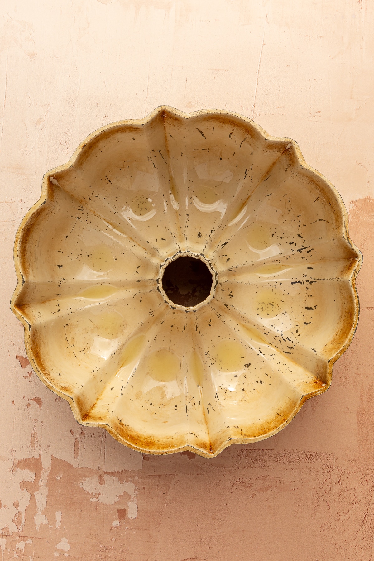 An off white/light yellow bundt cake pan coated with oil.