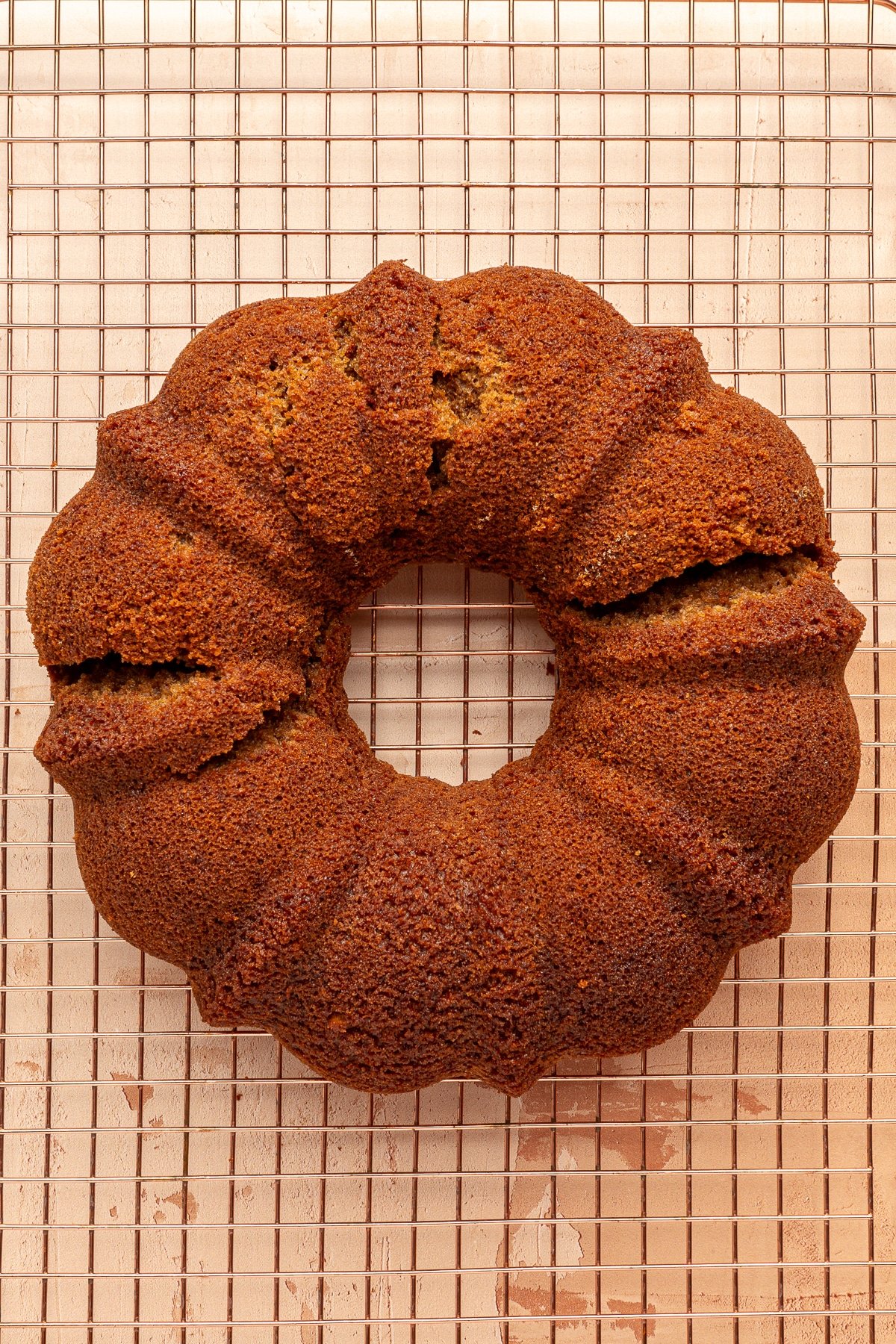 A pumpkin spice bundt cake, without the crumble or icing, cooling on a wire rack.