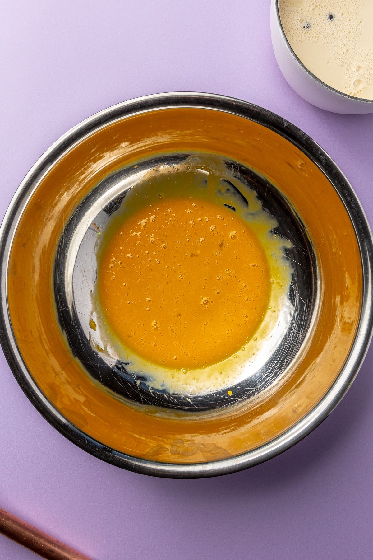 The egg yolks have been whisked together in the metal mixing bowl.