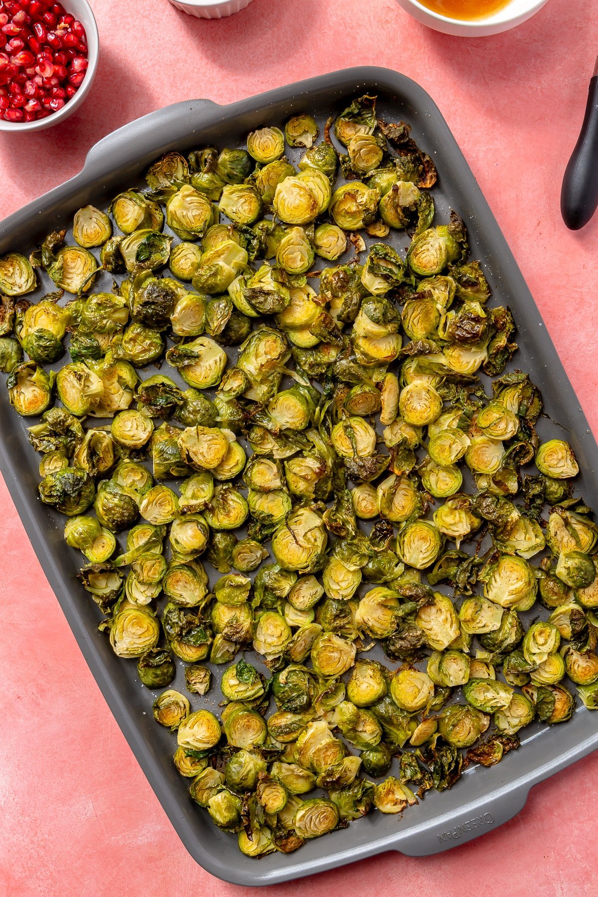 Roasted, crispy, golden-brown brussels sprouts sit on a baking tray.