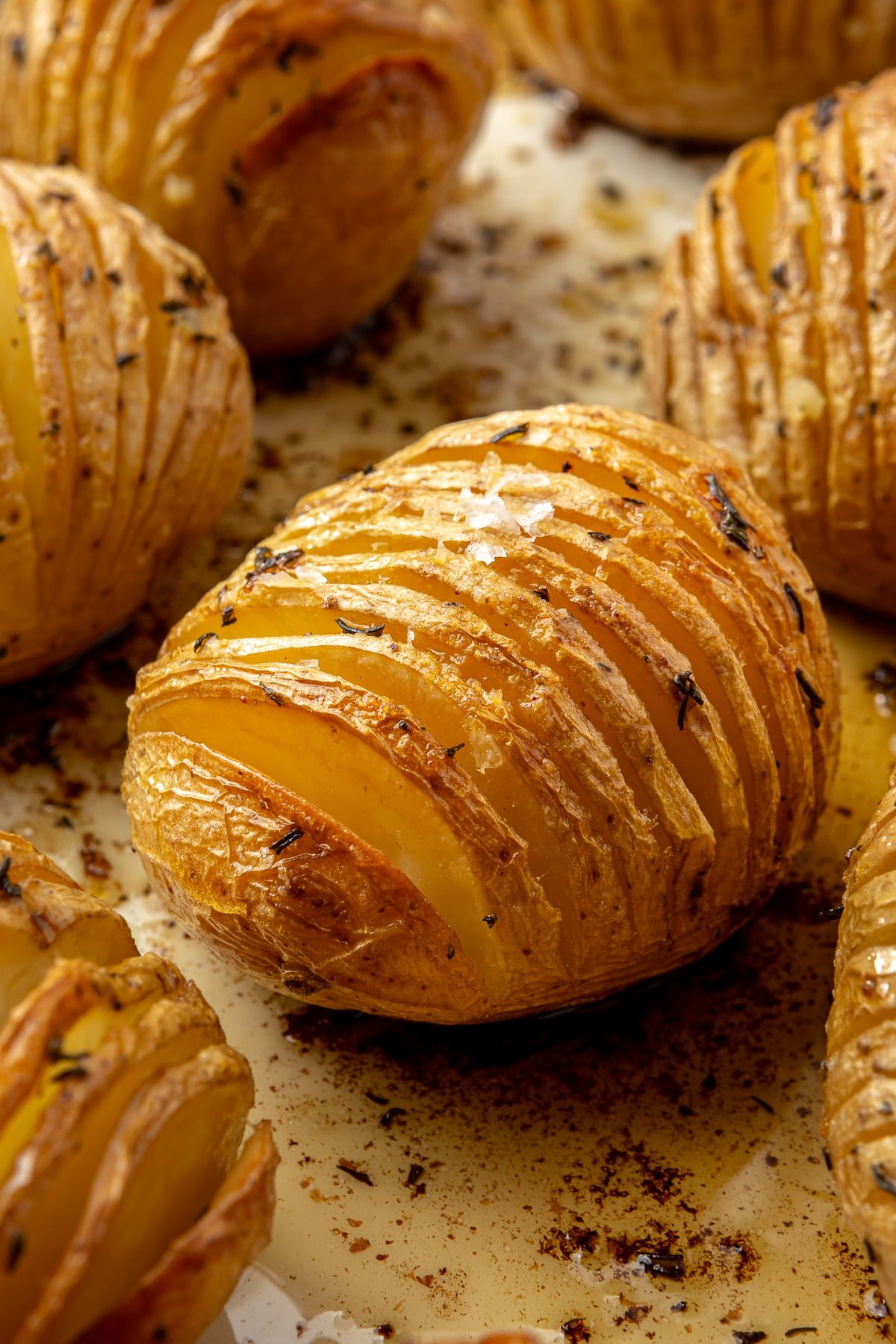 Fully baked, golden brown potatoes sit on a baking tray. Flaky salt has been sprinkled on top.
