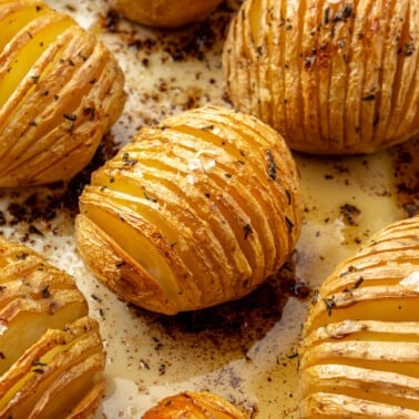 Fully baked, golden brown potatoes sit on a baking tray. Flaky salt has been sprinkled on top.