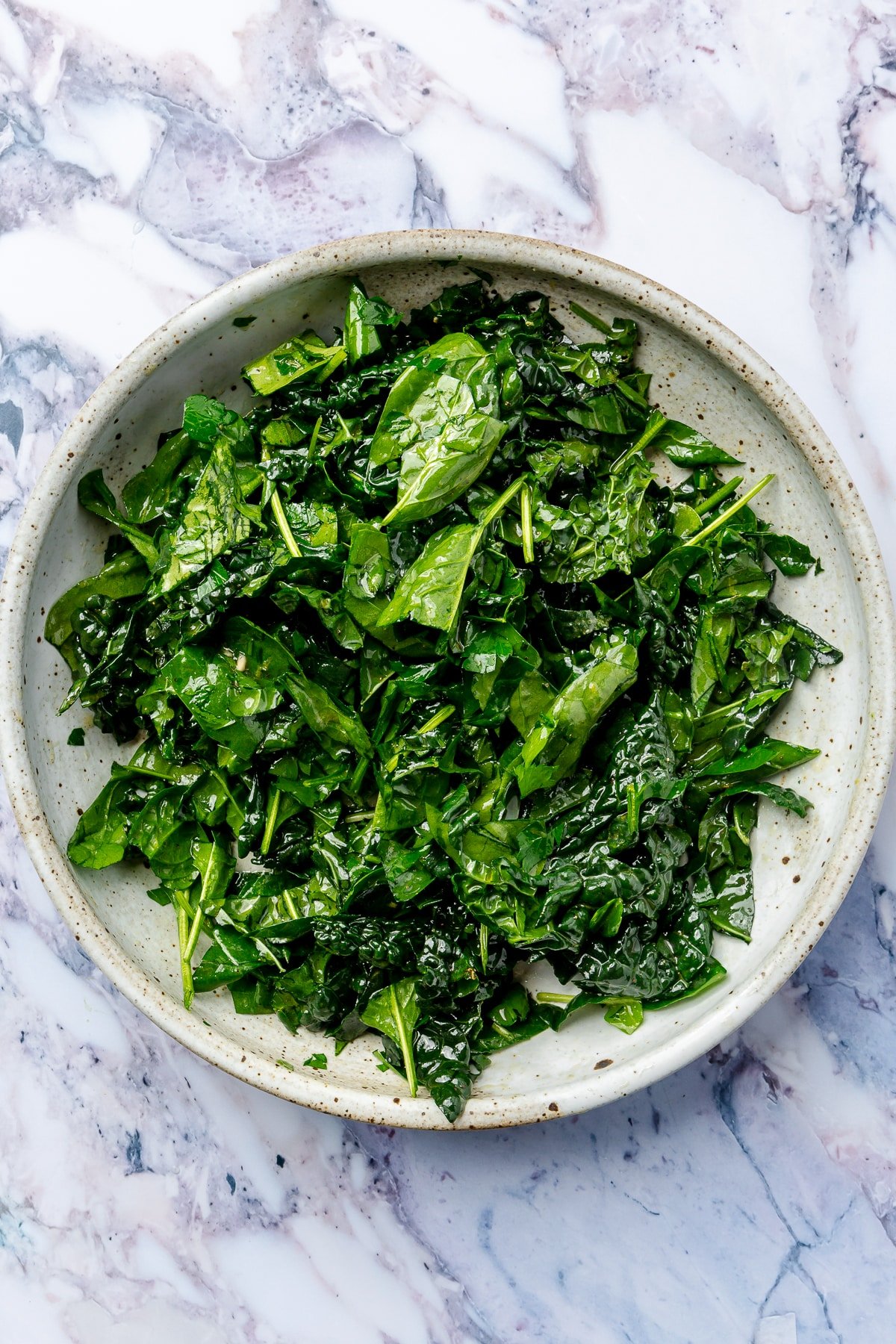 The, now chopped, spinach has been added to the bowl of kale.