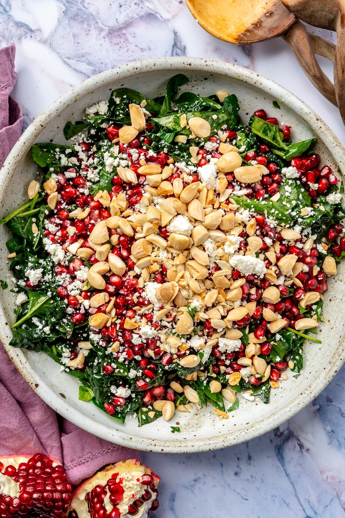 The remaining ingredients, including pomegranate seeds and chopped almond, have been added to the top of the kale.