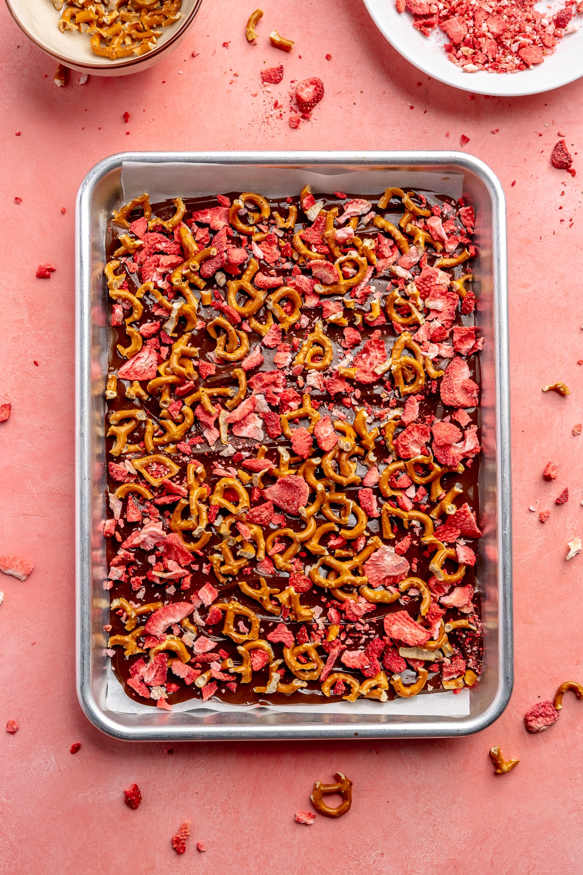 Freeze dried strawberries and broken pretzel pieces have been sprinkled over the top of the chocolate layer.