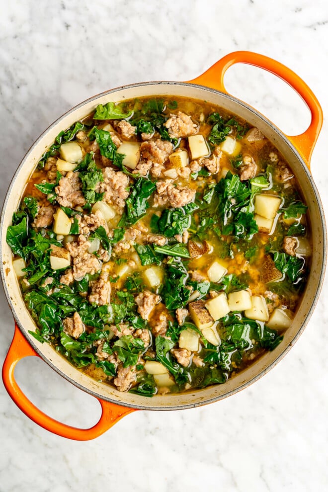 A pot of creamy sausage and kale soup before the cream is added in.