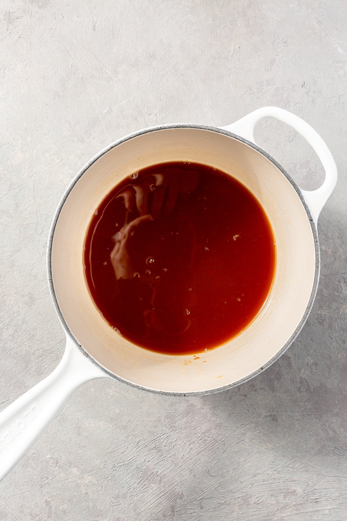 A dark red liquid sits in the bottom of a white pot.