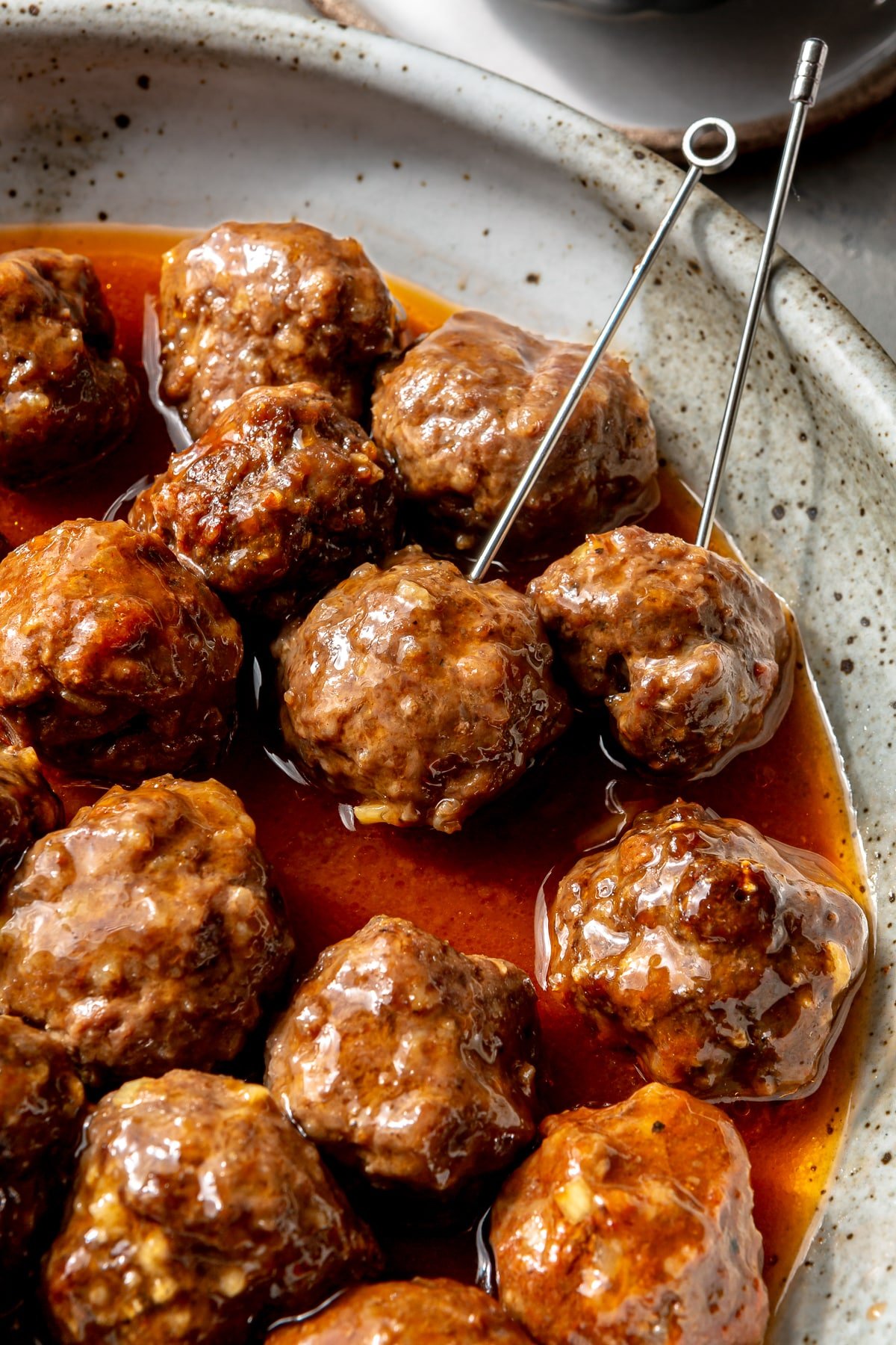 Sweet and sour meatballs have been placed in a serving bowl. Serving skewers have been placed in a couple.