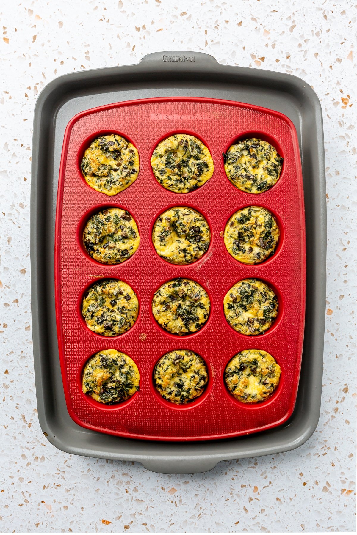 Fully baked egg bites sit in a red muffin tray.