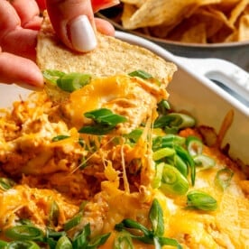 A person using a tortilla chip to scoop buffalo chicken dip.