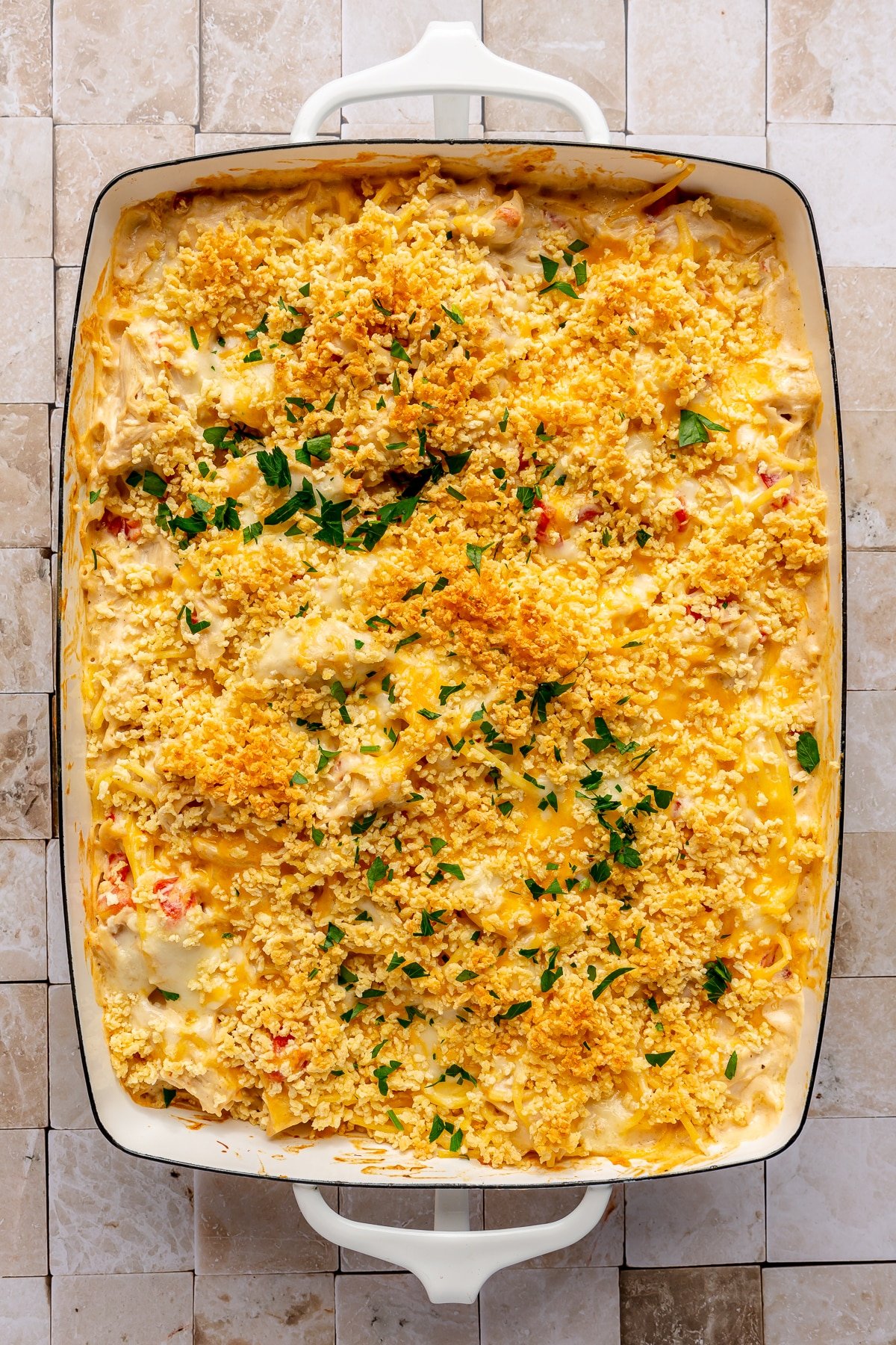 The chicken mixture, topped with breadcrumbs, has been fully baked to a golden brown and topped with chopped parsley.