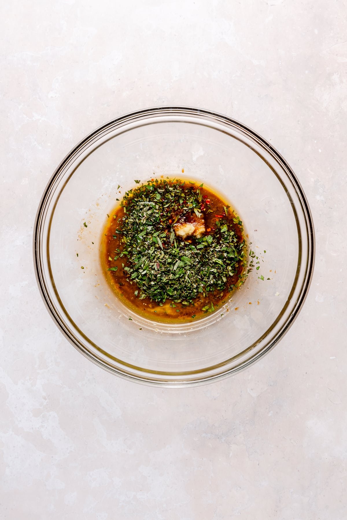 A variety of herby ingredients sit in a glass bowl.