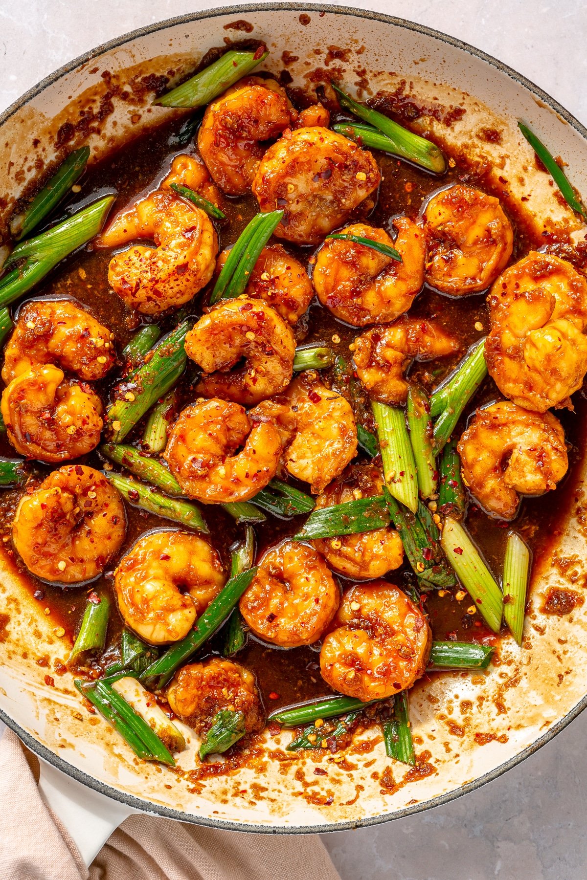 Honey garlic shrimp and green onions in a white skillet.