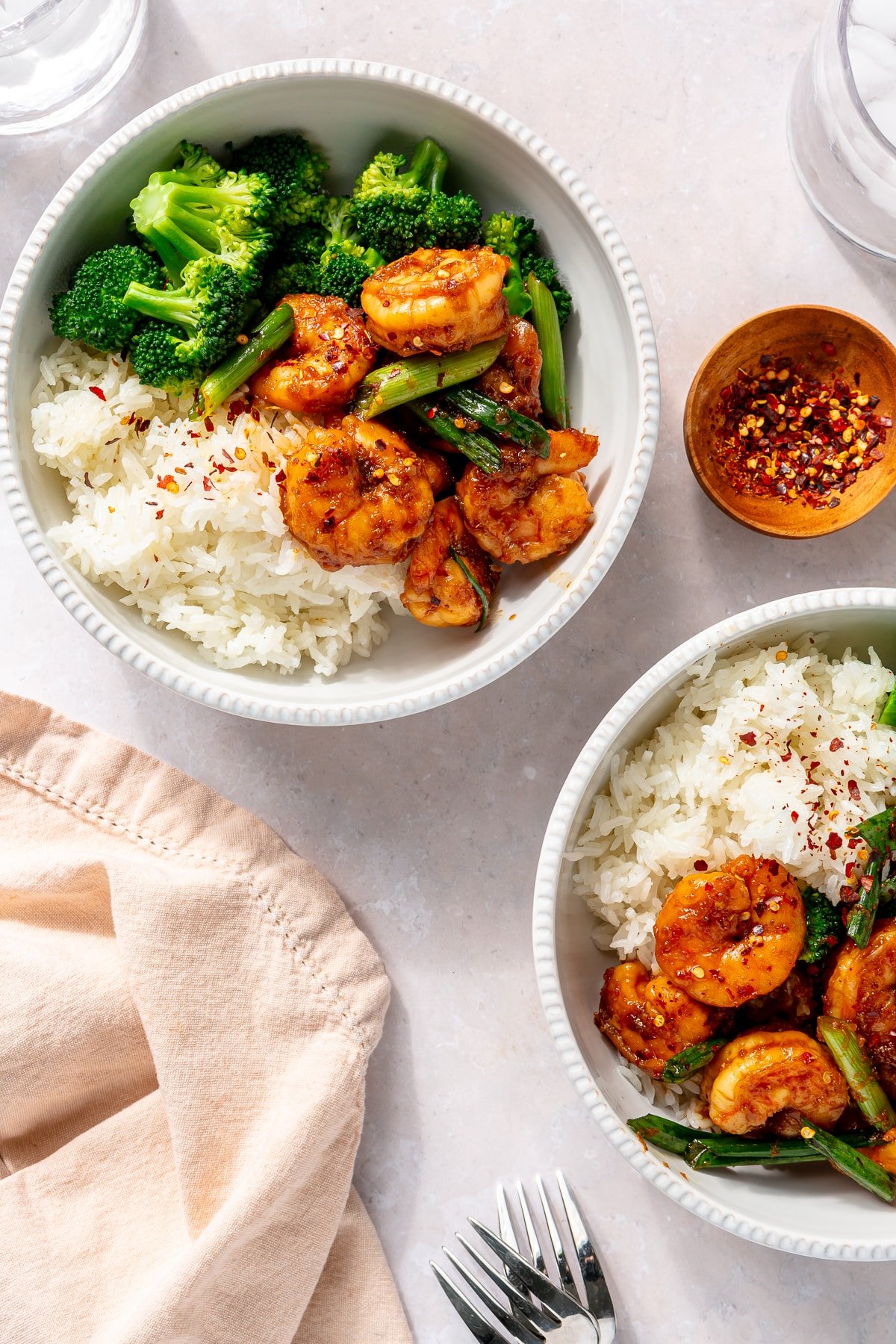 Two bowls filled with white rice, steamed broccoli, and honey garlic shrimp.