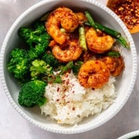 A white bowl filled with white rice, steamed broccoli, and honey garlic shrimp.